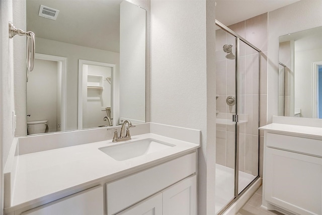 bathroom with vanity, a shower with door, and toilet