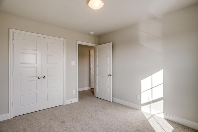 unfurnished bedroom featuring light colored carpet and a closet