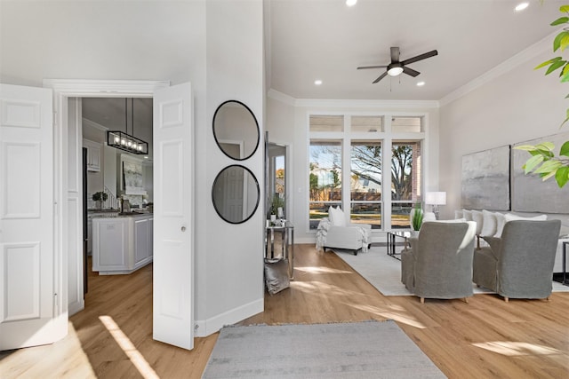 living room featuring ceiling fan with notable chandelier, light wood-type flooring, and crown molding