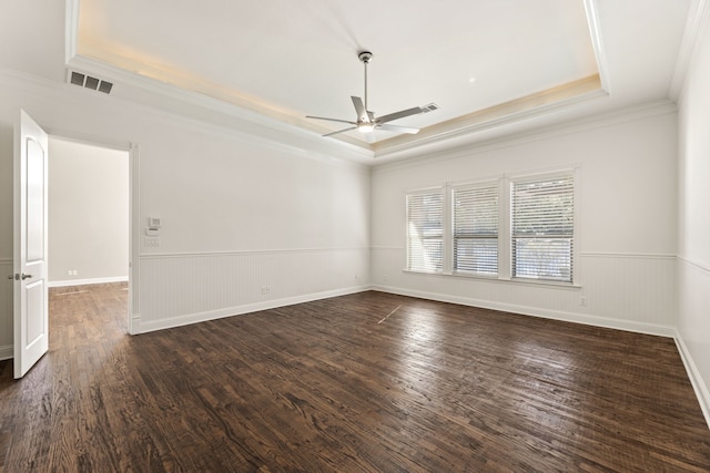 spare room featuring a tray ceiling, ceiling fan, dark hardwood / wood-style floors, and ornamental molding