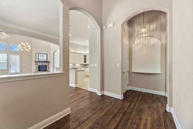 hall featuring ornamental molding, dark wood-type flooring, and a notable chandelier