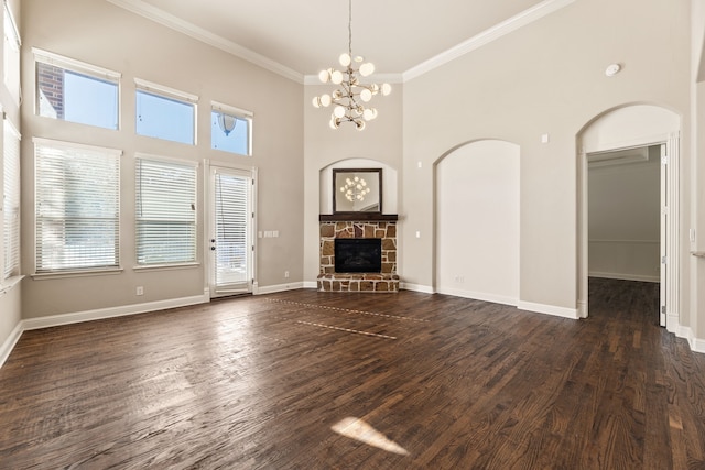 unfurnished living room with a towering ceiling, crown molding, an inviting chandelier, a fireplace, and dark hardwood / wood-style floors