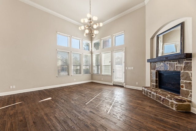 unfurnished living room featuring a stone fireplace, crown molding, dark hardwood / wood-style flooring, and a chandelier