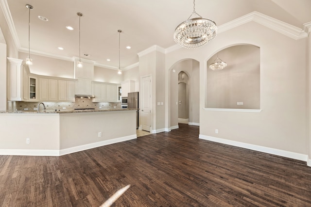 kitchen featuring light stone countertops, decorative backsplash, ornamental molding, dark hardwood / wood-style floors, and hanging light fixtures