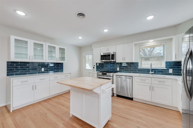 kitchen featuring a healthy amount of sunlight, white cabinetry, appliances with stainless steel finishes, and light hardwood / wood-style flooring