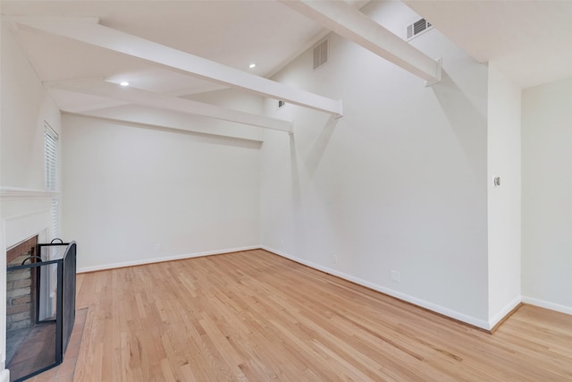 unfurnished living room featuring beamed ceiling and light wood-type flooring