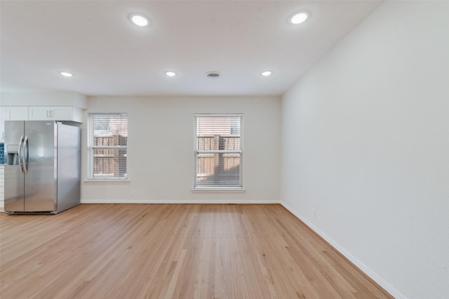 kitchen with stainless steel fridge, light hardwood / wood-style flooring, white cabinets, and a healthy amount of sunlight