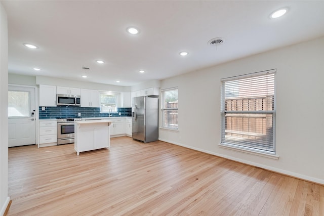 kitchen with a center island, light wood-type flooring, white cabinetry, and stainless steel appliances