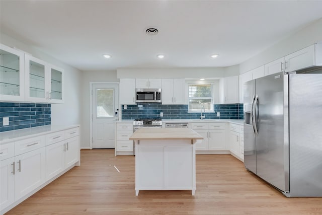 kitchen with white cabinets, stainless steel appliances, light wood-type flooring, and a kitchen island