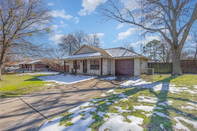 ranch-style home with a front yard, a garage, and central AC unit