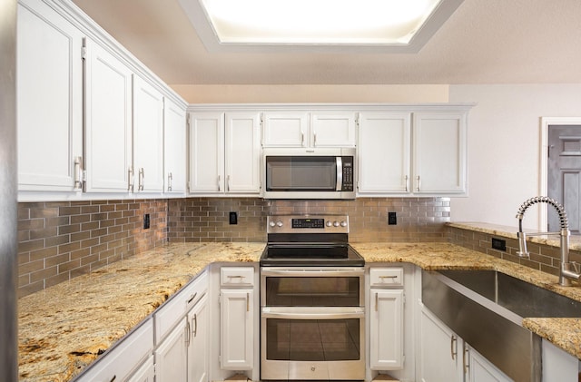 kitchen featuring tasteful backsplash, white cabinetry, sink, and stainless steel appliances