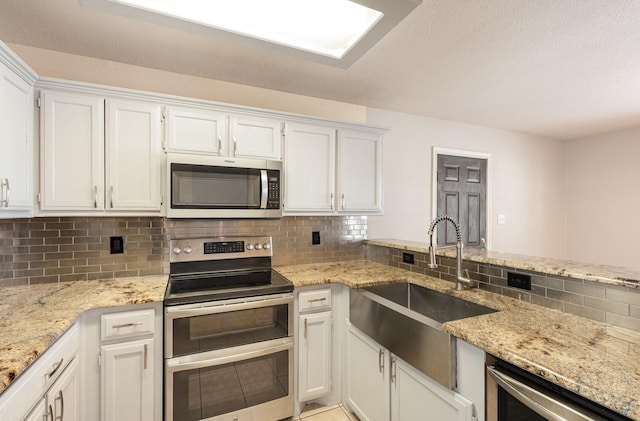 kitchen featuring decorative backsplash, light stone counters, stainless steel appliances, sink, and white cabinets