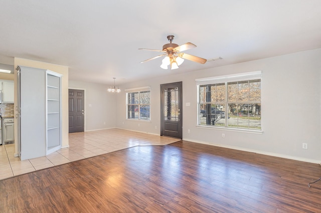 interior space with ceiling fan with notable chandelier and light wood-type flooring