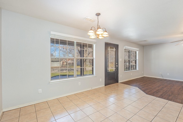 unfurnished room featuring light tile patterned floors and ceiling fan with notable chandelier