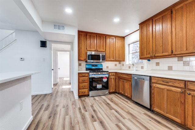 kitchen featuring sink, stainless steel appliances, tasteful backsplash, and light hardwood / wood-style flooring