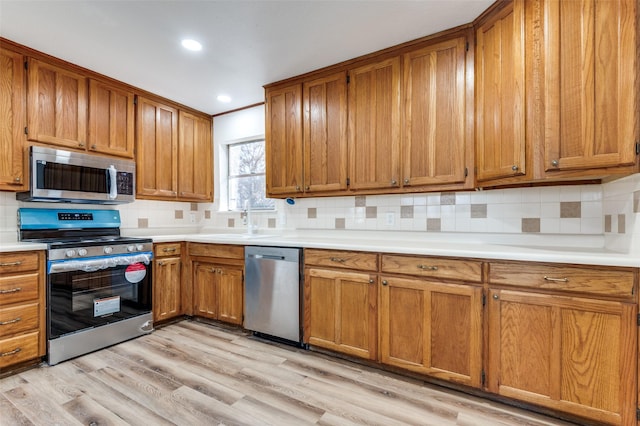 kitchen with stainless steel appliances, tasteful backsplash, light hardwood / wood-style floors, and sink