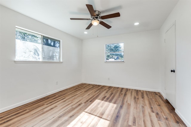 spare room with ceiling fan, light wood-type flooring, and a wealth of natural light