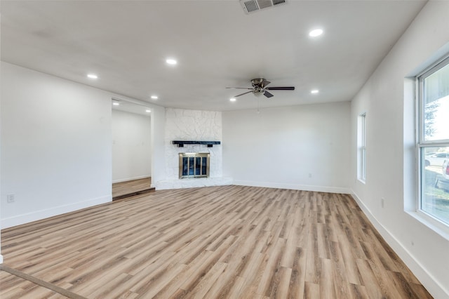 unfurnished living room with ceiling fan, a fireplace, and light hardwood / wood-style flooring