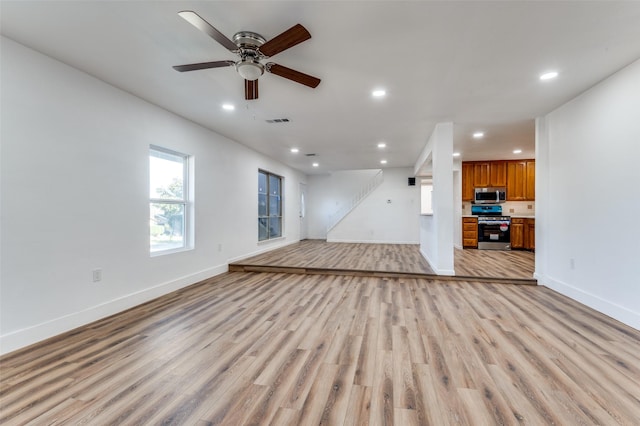 unfurnished living room featuring ceiling fan and light wood-type flooring