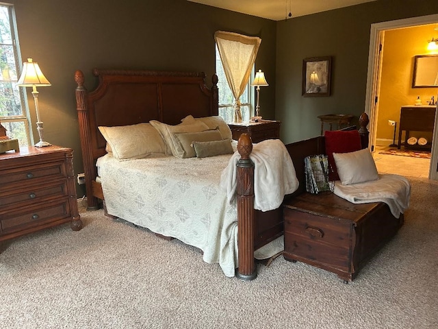 bedroom with ensuite bath and light carpet