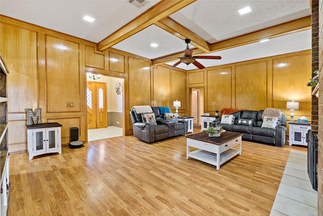 living room with beamed ceiling, a textured ceiling, light wood-type flooring, and ceiling fan