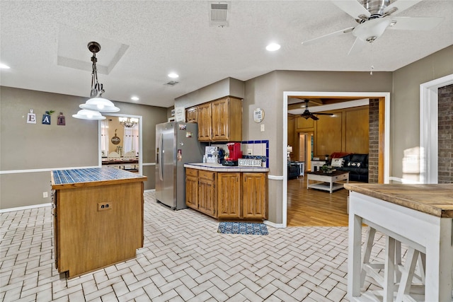 kitchen with decorative light fixtures, stainless steel fridge, a textured ceiling, and ceiling fan