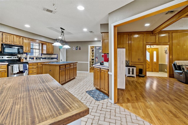 kitchen with stainless steel electric stove, sink, pendant lighting, light hardwood / wood-style flooring, and a kitchen island