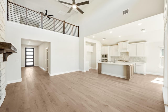 kitchen with a high ceiling, visible vents, appliances with stainless steel finishes, and light wood-type flooring