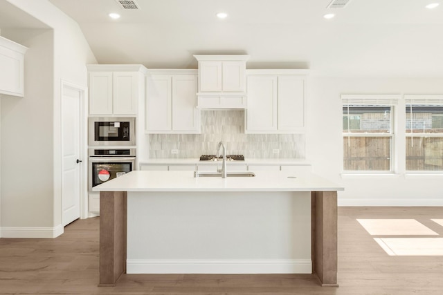 kitchen with black microwave, oven, a sink, light countertops, and tasteful backsplash