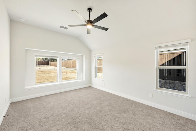 carpeted empty room featuring lofted ceiling, visible vents, ceiling fan, and baseboards