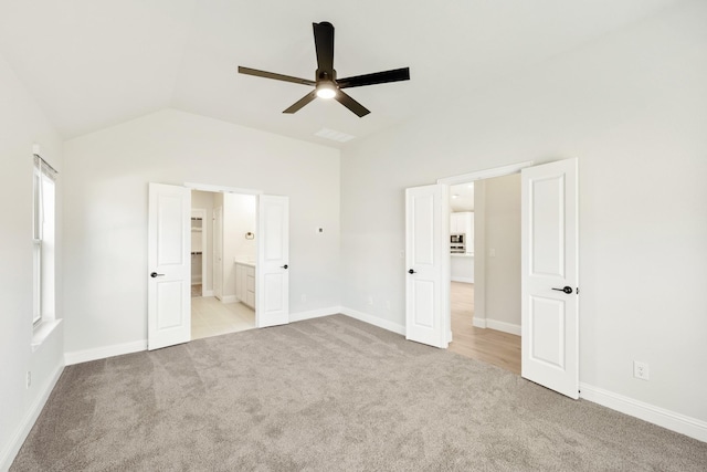 unfurnished bedroom featuring light colored carpet, baseboards, connected bathroom, and vaulted ceiling