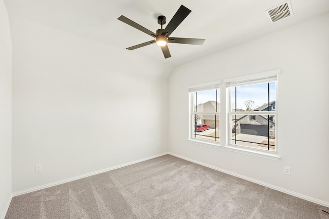 carpeted empty room with visible vents, baseboards, ceiling fan, and vaulted ceiling