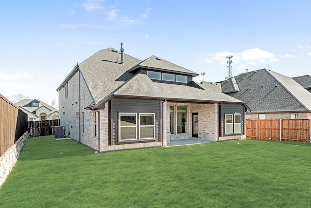 rear view of property with brick siding, a lawn, a fenced backyard, and roof with shingles