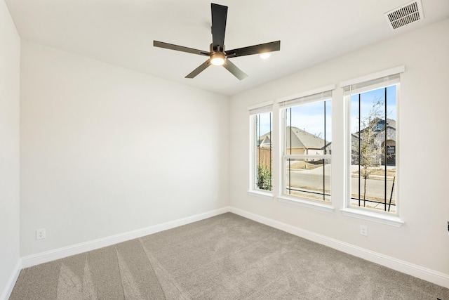 carpeted empty room with baseboards, visible vents, and a ceiling fan