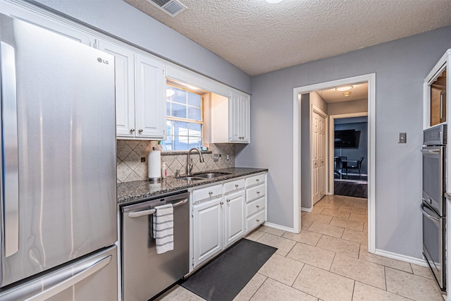 kitchen with sink, white cabinets, appliances with stainless steel finishes, and tasteful backsplash