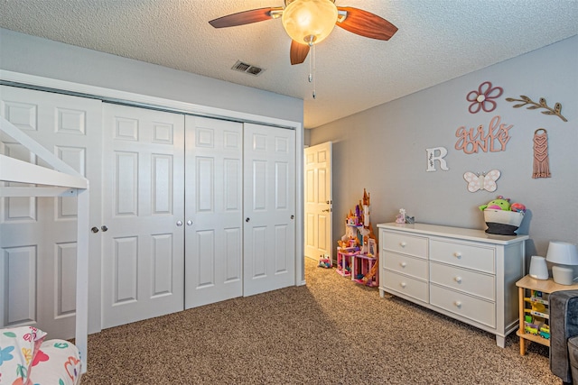 carpeted bedroom with ceiling fan, a closet, and a textured ceiling