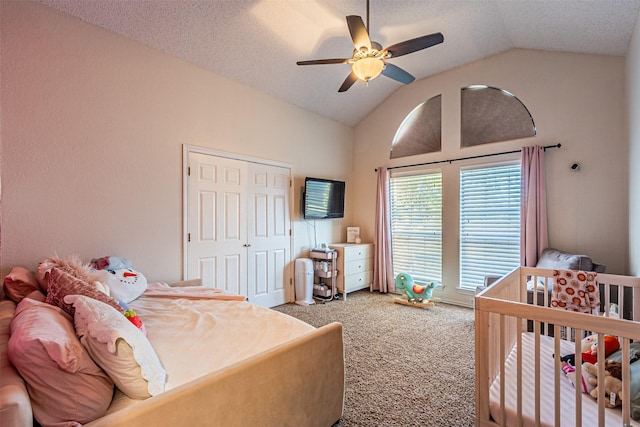 carpeted bedroom with ceiling fan, a textured ceiling, a closet, and lofted ceiling