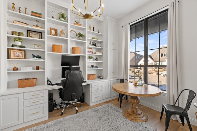 office featuring built in desk, light wood-type flooring, built in features, and a chandelier