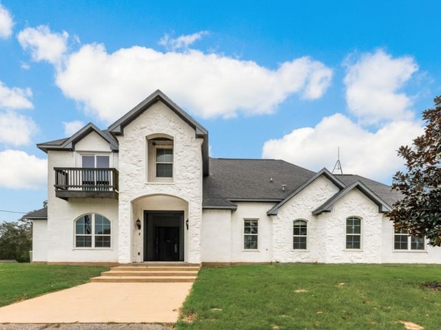 french country inspired facade with a balcony and a front lawn