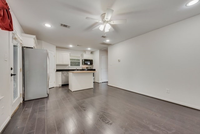 kitchen featuring white cabinetry, a center island, ceiling fan, stainless steel appliances, and dark wood-type flooring