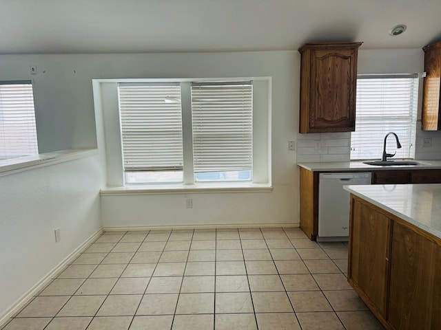 kitchen featuring sink, white dishwasher, plenty of natural light, and light tile patterned floors