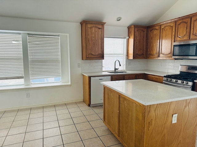 kitchen featuring appliances with stainless steel finishes, tasteful backsplash, vaulted ceiling, sink, and a center island