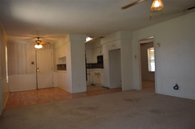 unfurnished living room featuring ceiling fan and light colored carpet