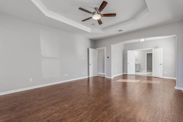 unfurnished room with dark wood-type flooring, a raised ceiling, ceiling fan, and crown molding