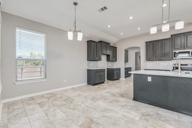 kitchen with appliances with stainless steel finishes, backsplash, sink, decorative light fixtures, and lofted ceiling