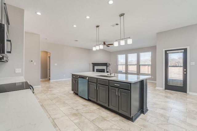 kitchen featuring stainless steel dishwasher, ceiling fan, sink, hanging light fixtures, and an island with sink