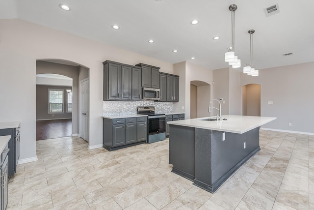 kitchen featuring appliances with stainless steel finishes, tasteful backsplash, sink, a center island with sink, and hanging light fixtures