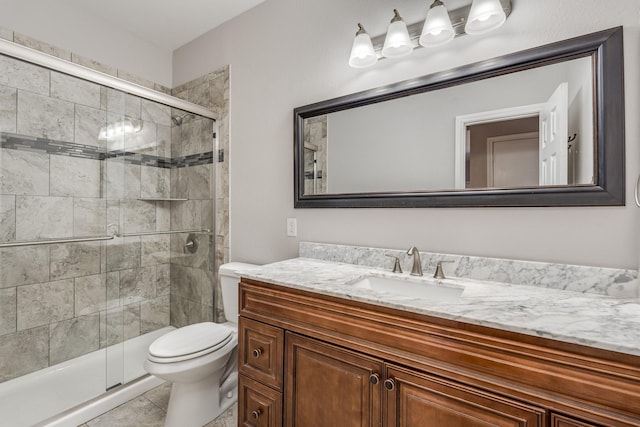 bathroom featuring tile patterned flooring, vanity, toilet, and a shower with door