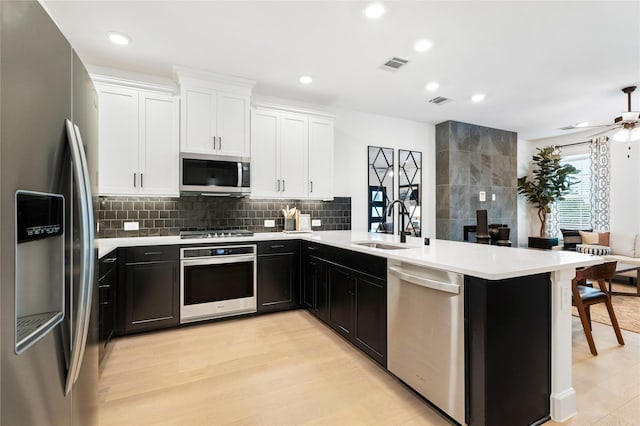 kitchen with light hardwood / wood-style floors, appliances with stainless steel finishes, kitchen peninsula, and sink