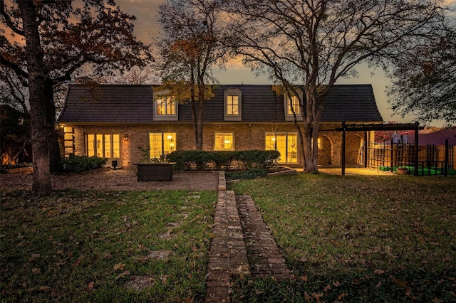 back house at dusk with a lawn and a patio area